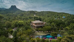 A resort with a swimming pool, lush greenery, and a mountain backdrop. - Popa Garden Resort (Kyaukpadaung)