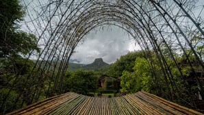 A traditional bamboo structure with a view of a mountain and lush greenery in the background. - Popa Garden Resort (Kyaukpadaung)