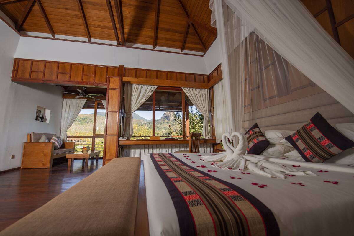 Una habitación con una cama grande, techo de madera y vistas al exterior.