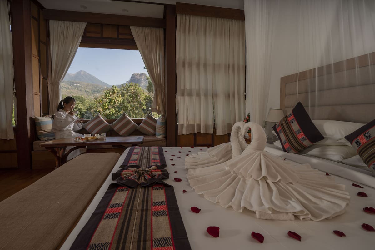 Habitación de hotel con cama, una mesa con comida y vistas a las montañas.