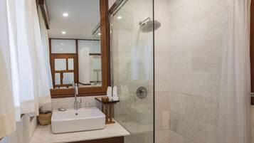 A modern bathroom with a glass-enclosed shower, a large mirror, and a wooden vanity with a sink.