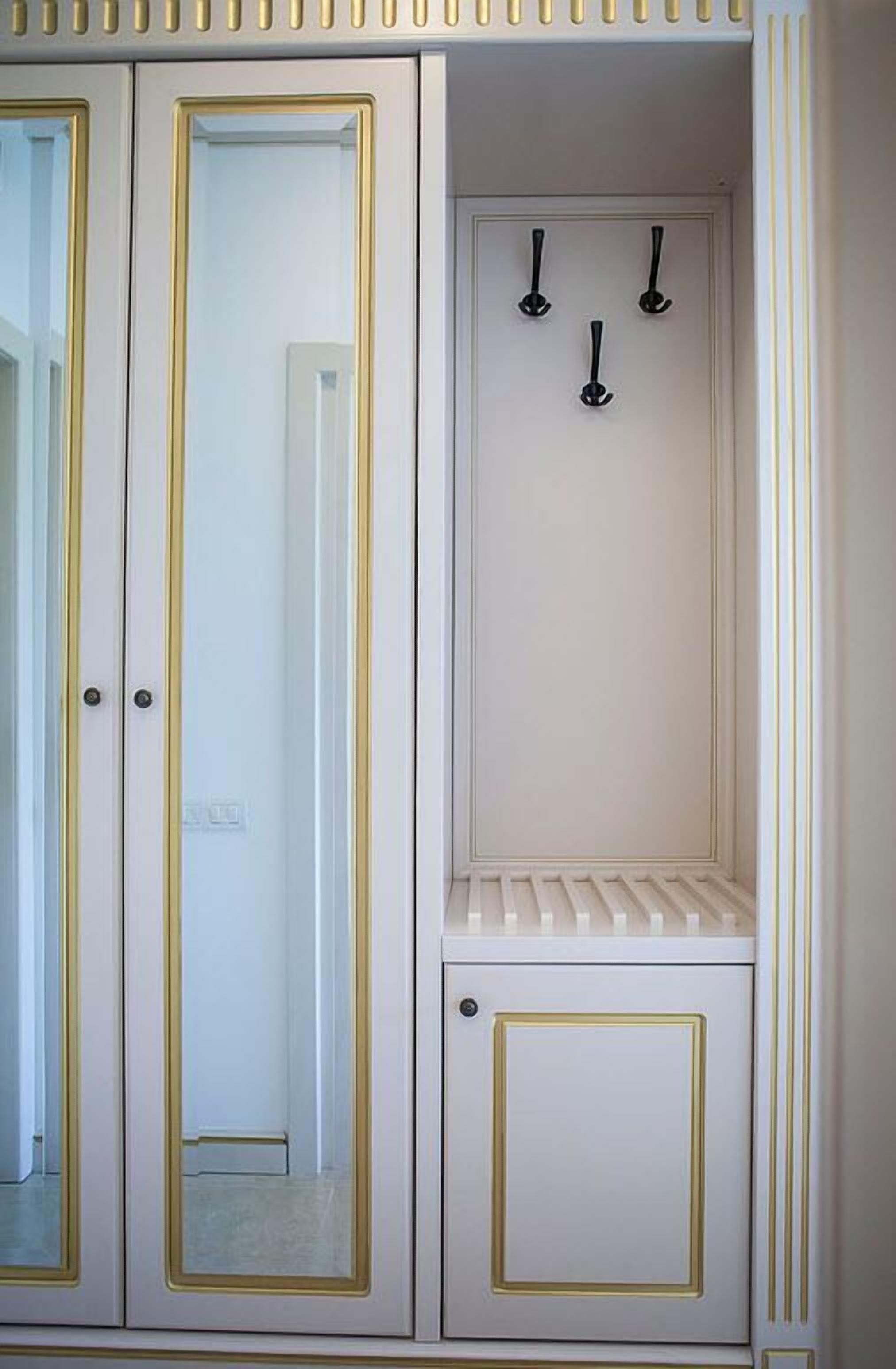 A white wardrobe with gold trim and a mirror.