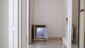 Ein Flur mit einer weißen Tür, einem kleinen Schrank und einer Heizung.