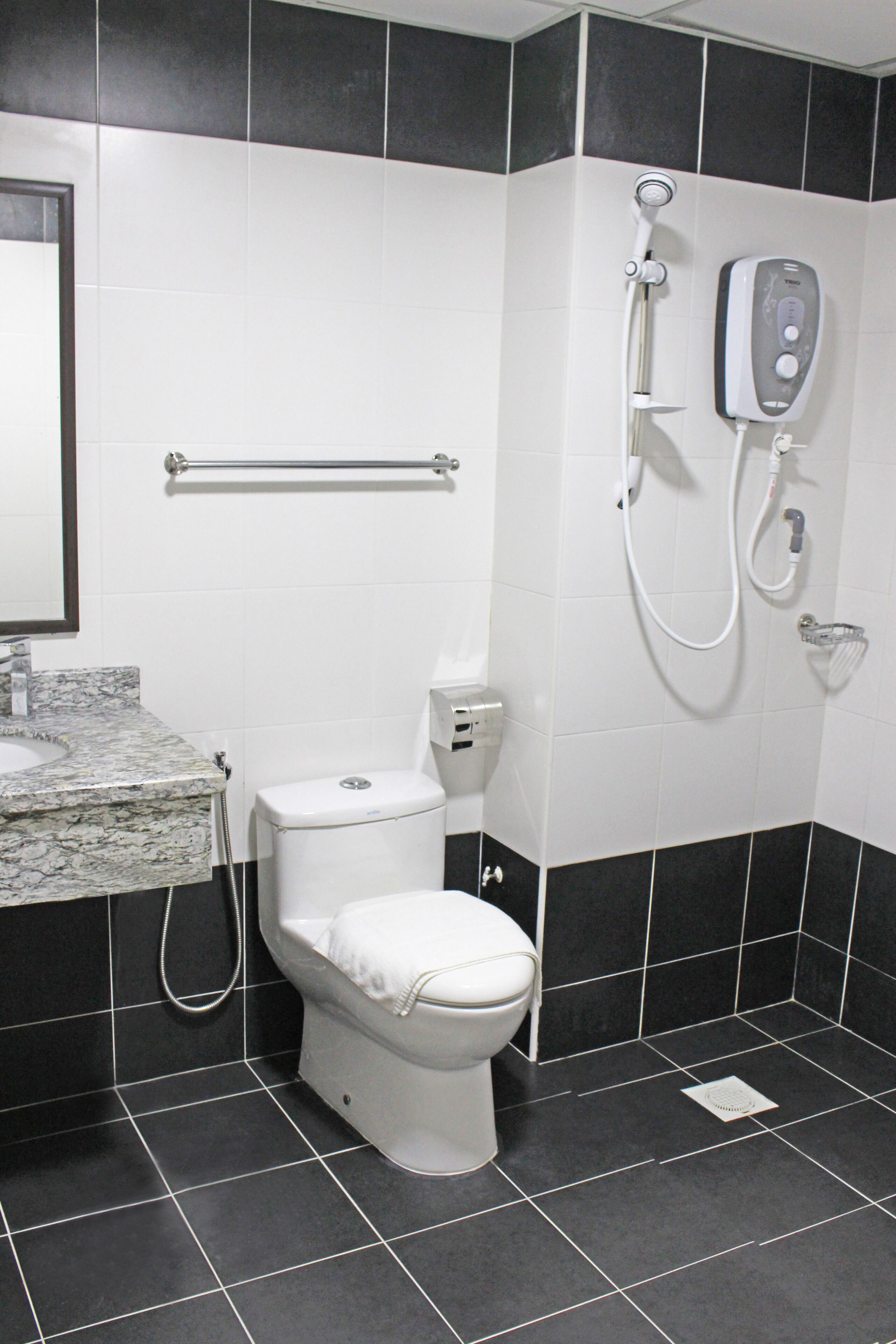 Ein Badezimmer mit Toilette, Handtrockner und Seifenspender.