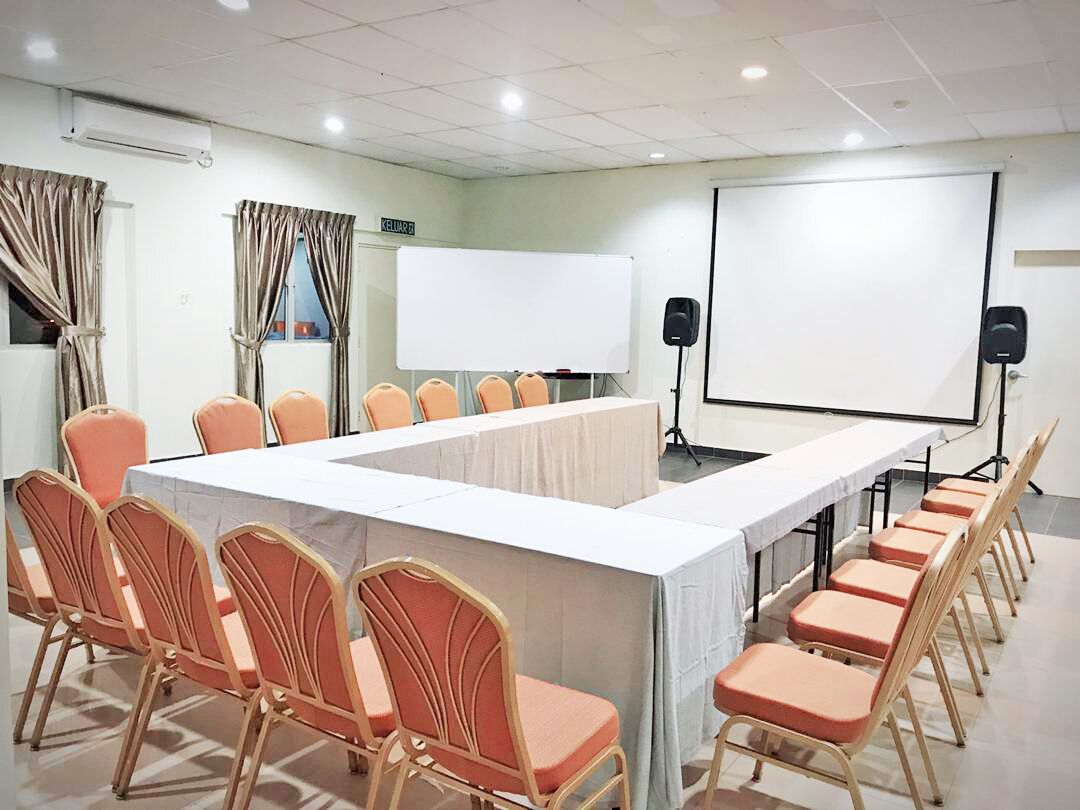 A conference room with a long table, chairs, a whiteboard, and a projector screen.