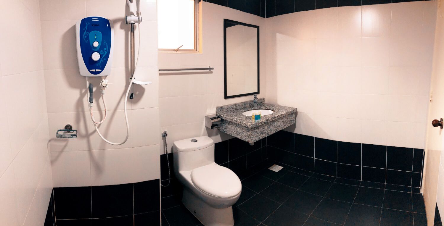 Een badkamer met een wit toilet, een wastafel met een granieten aanrechtblad, een handdouche en een spiegel boven de wastafel.