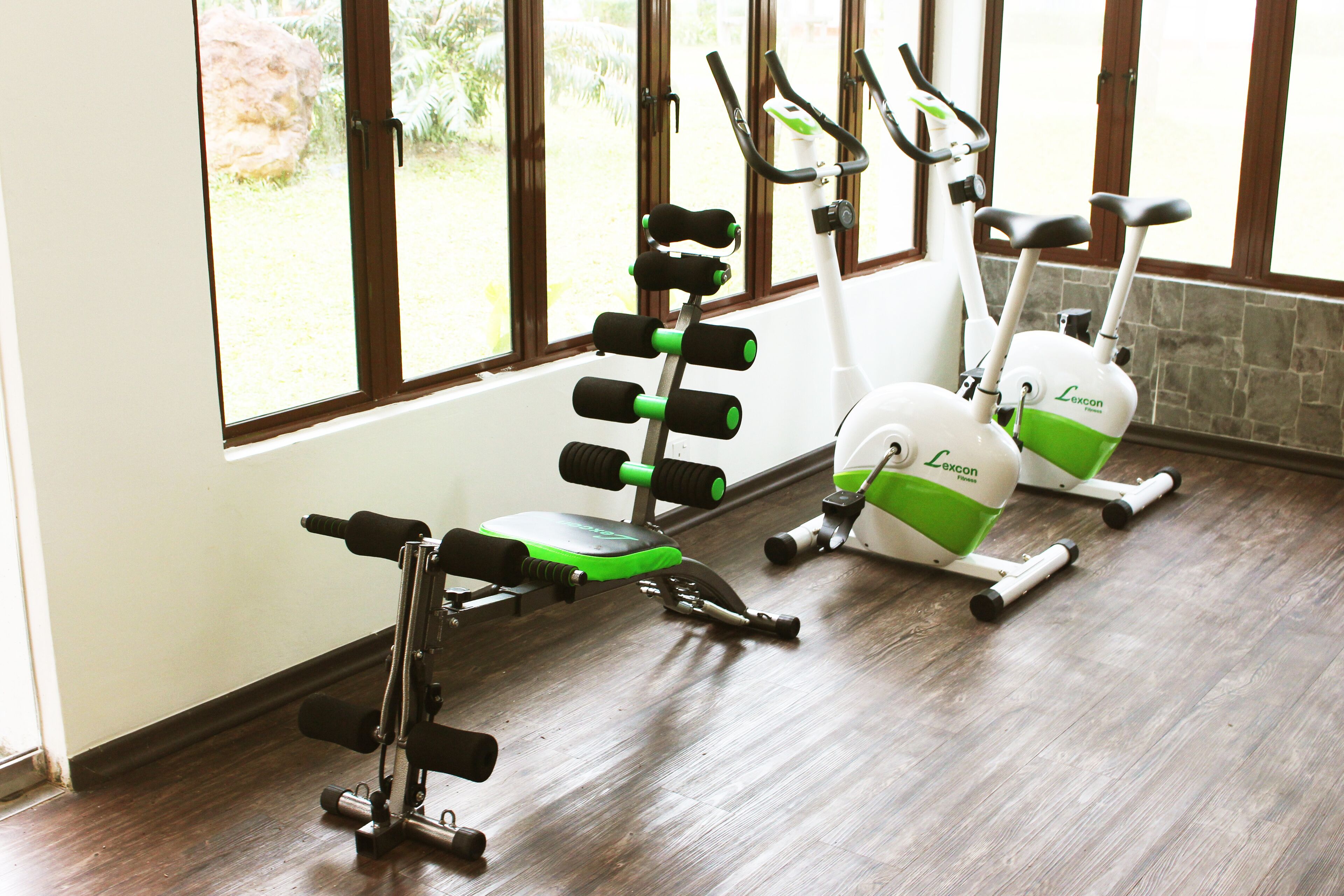 Un gimnasio con equipo de ejercicio y ventanas amplias.