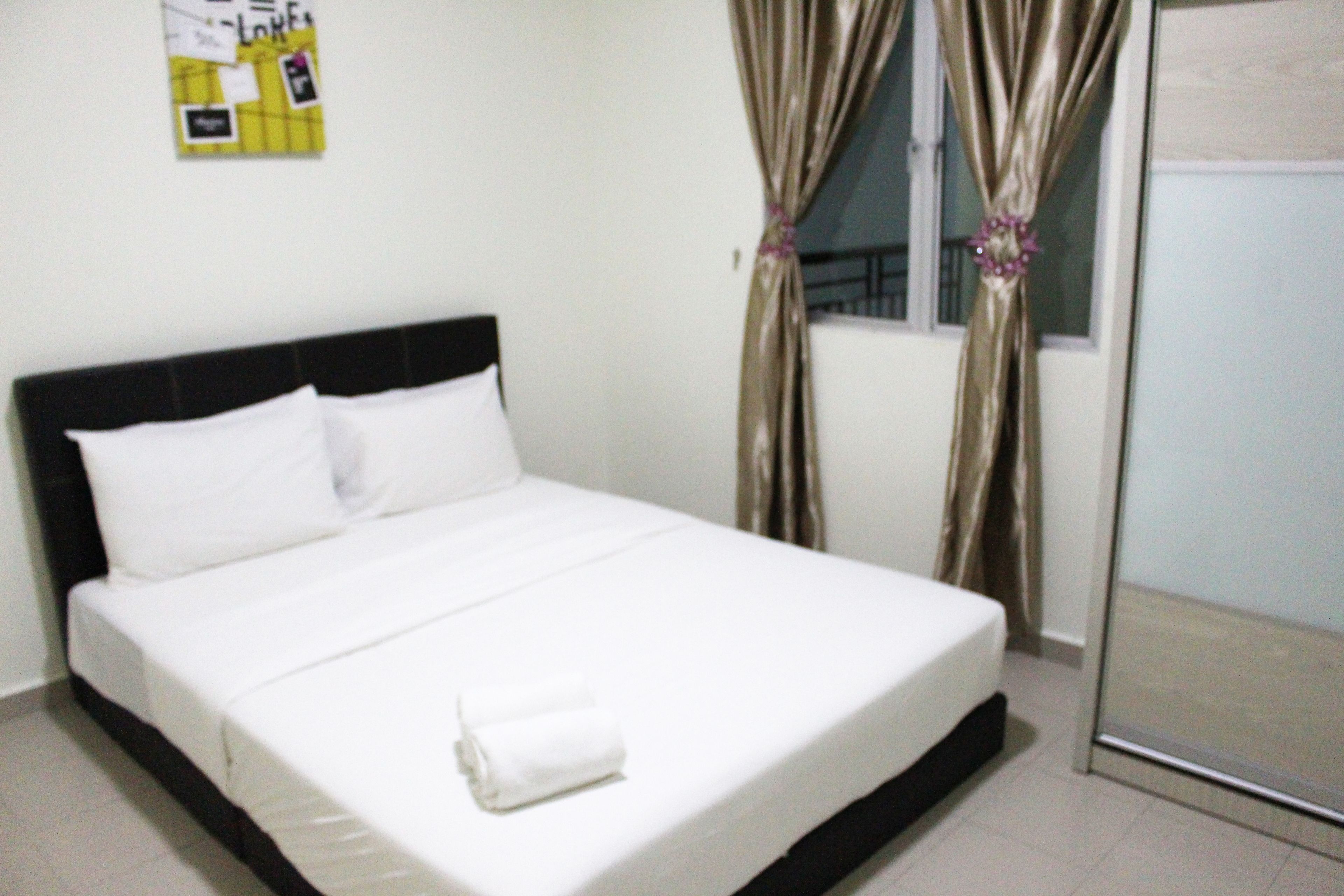 A neatly made bed with white linens, a black headboard, and a folded towel on the foot of the bed.