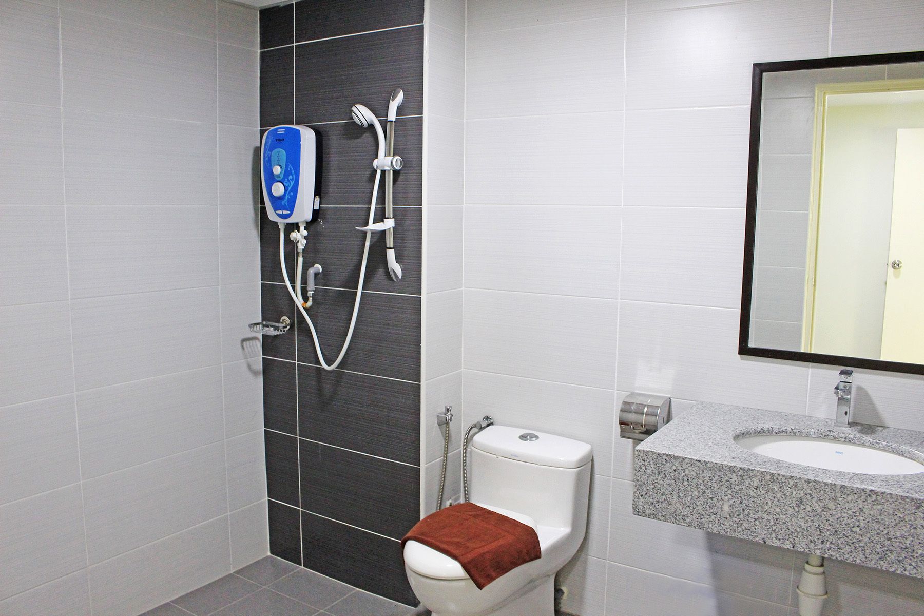 Un baño con ducha, inodoro, lavabo y espejo.