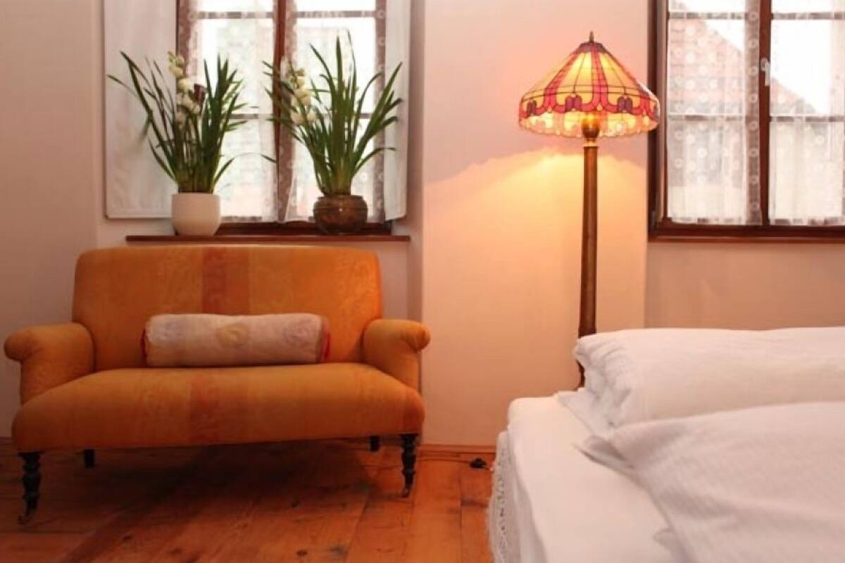 A room with a sofa, a lamp, and a bed.