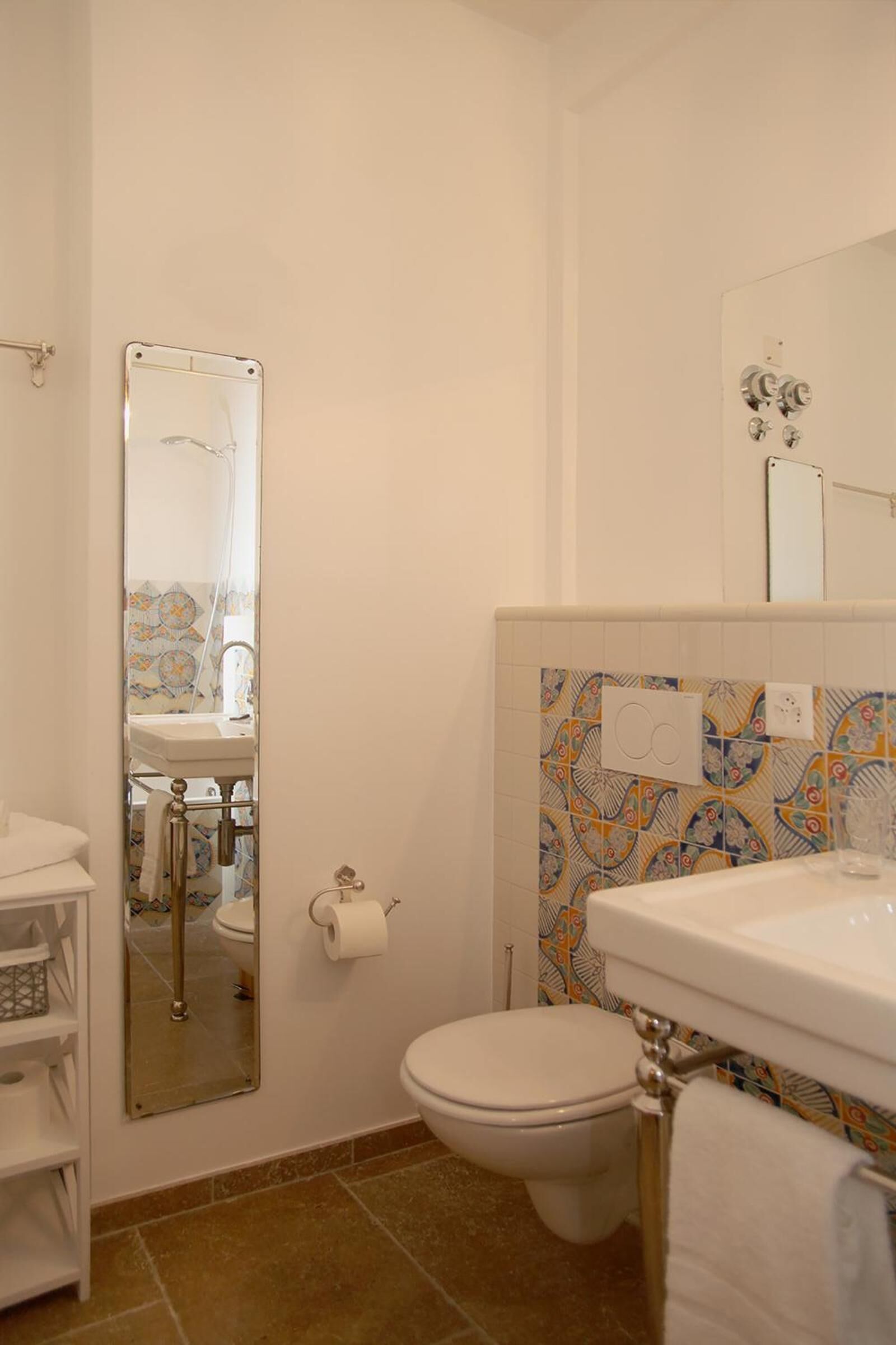 A bathroom with a toilet, sink, and mirror.