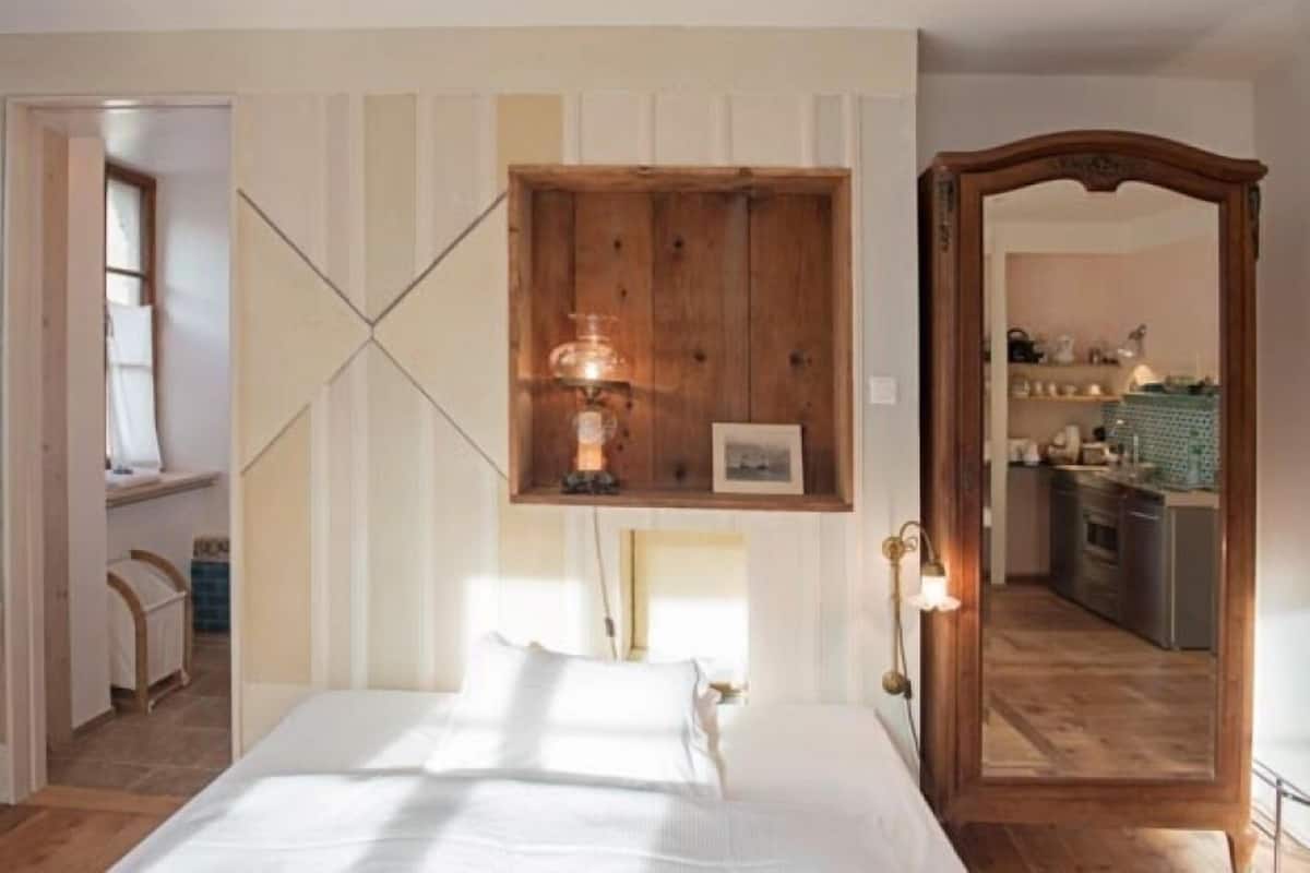 A bedroom with a wooden headboard, a bedside table, a lamp, and a framed picture on the wall.