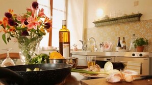 A kitchen with a stove, a sink, and a countertop with a bowl, a bottle, and a vase of flowers. - Guesthouse Le Locle (Le Locle)