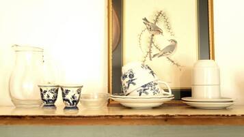 A dining table with a framed artwork, a pitcher, cups, and a teapot.