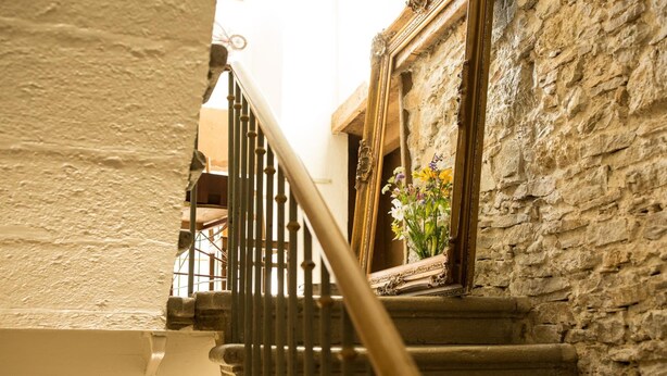 A staircase with a wooden railing leading to a stone building with a window displaying flowers. - Guesthouse Le Locle (Le Locle)