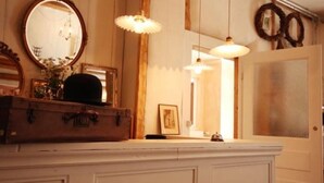 A vintage-style room with a wooden dresser, a mirror, and hanging lamps. - Guesthouse Le Locle (Le Locle)