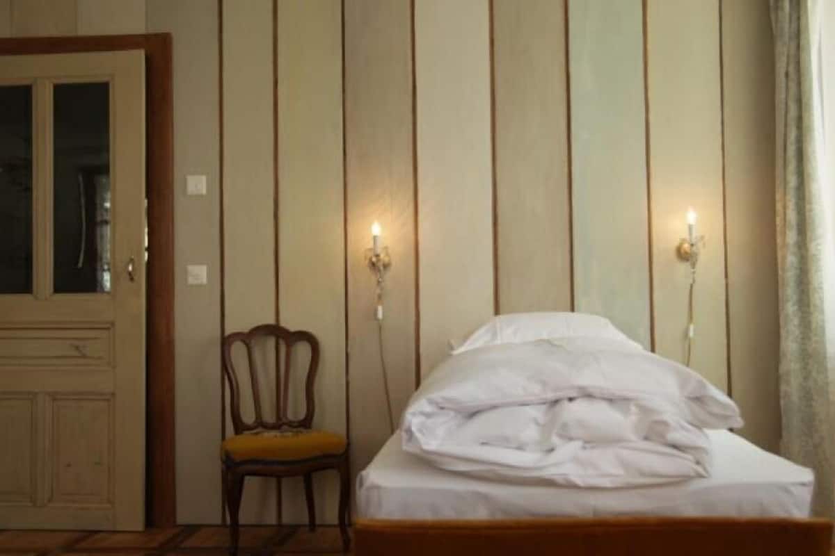A room with a bed, a chair, and a door.