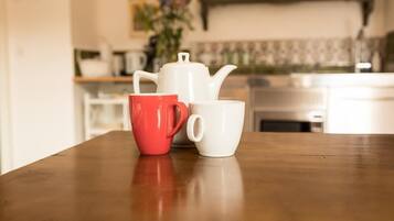 Une table en bois avec deux tasses, une rouge et une blanche, dans une cuisine.
