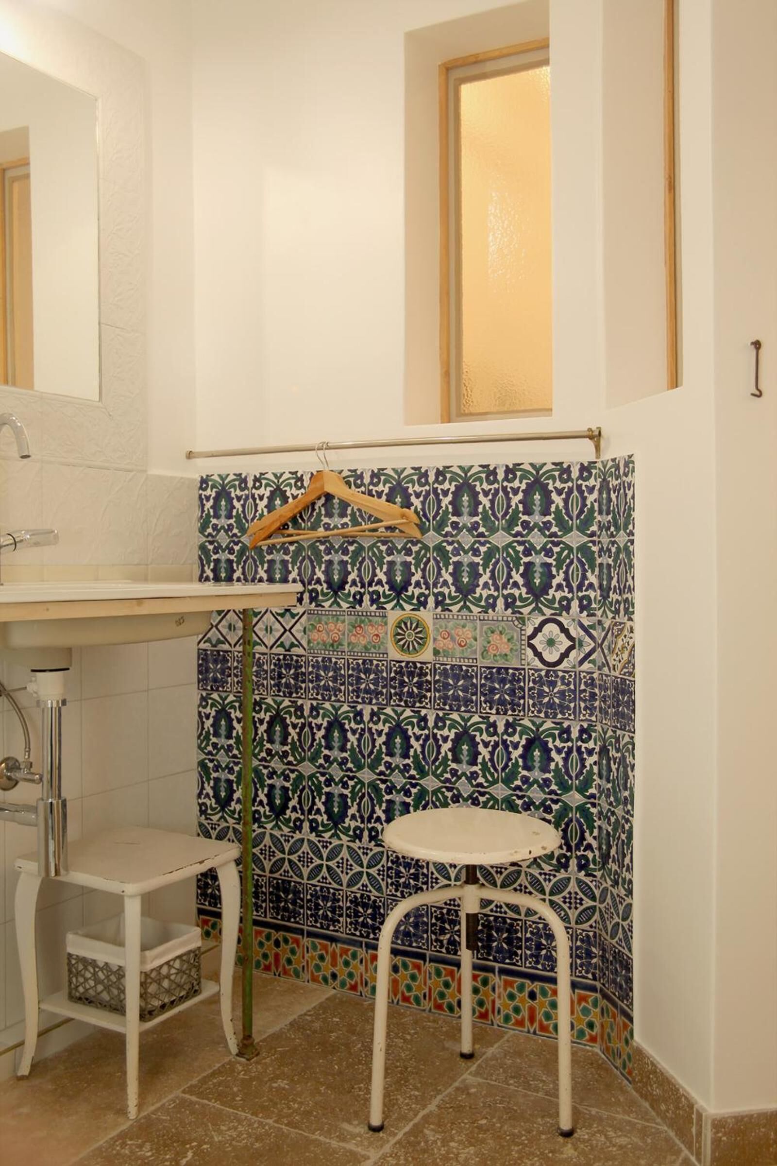 A bathroom with a sink, mirror, and a patterned tile wall.