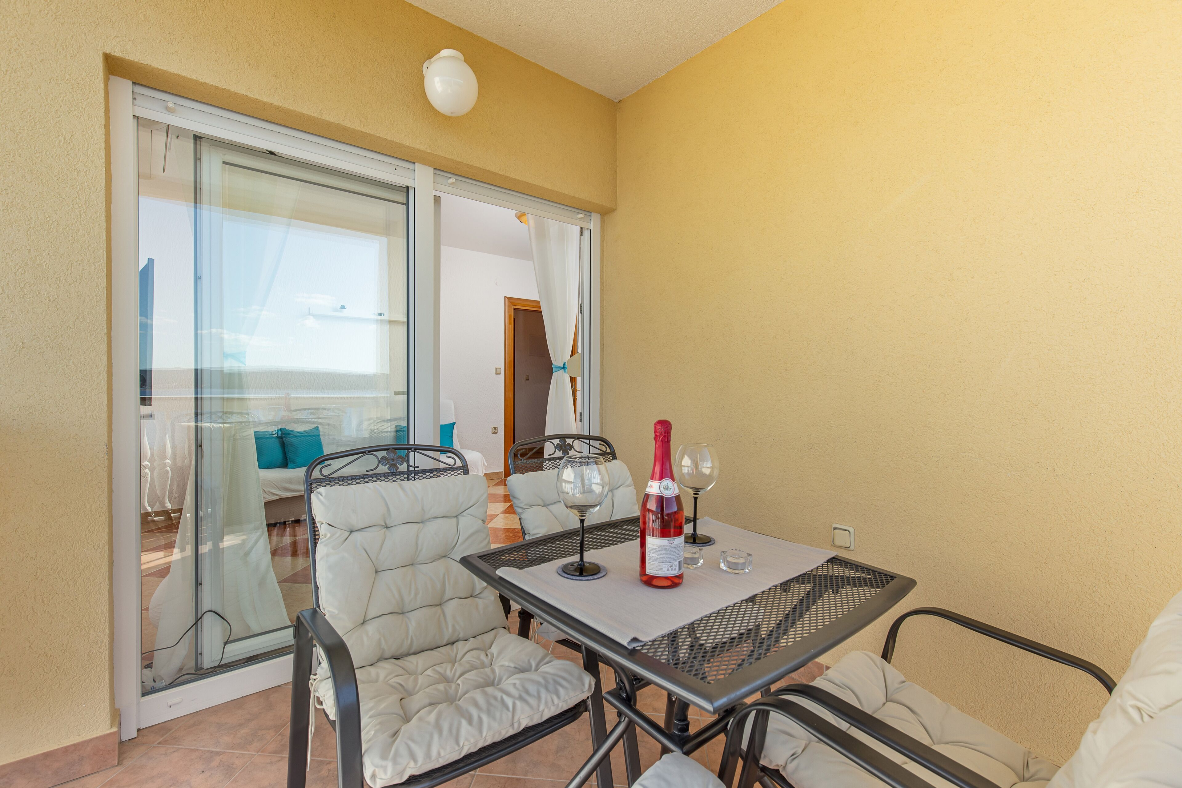Ein Balkon mit Tisch, Stühlen und einer Weinflasche.