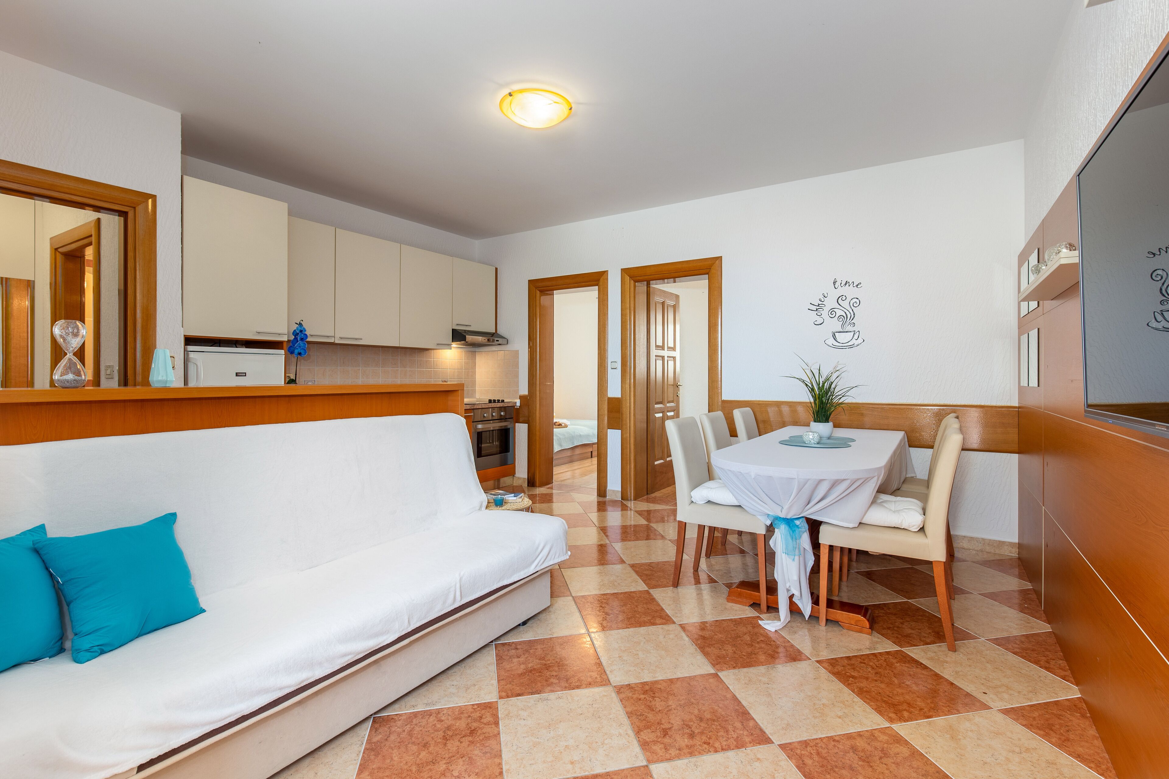 A compact living space with a kitchenette, a dining area, and a sofa with a blue cushion.