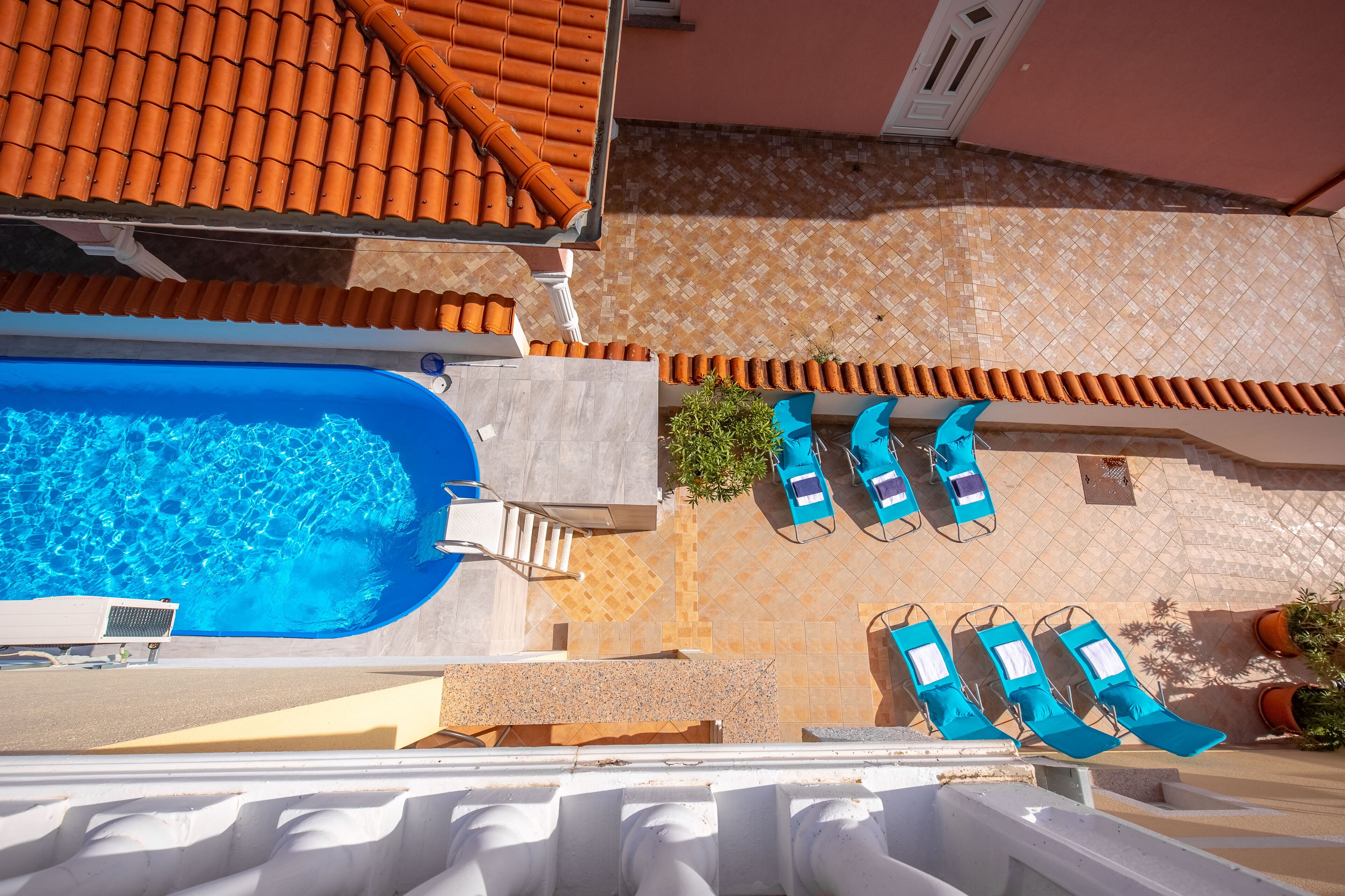 Une piscine sur le toit, avec une eau bleue, entourée de chaises longues et d’une terrasse carrelée.