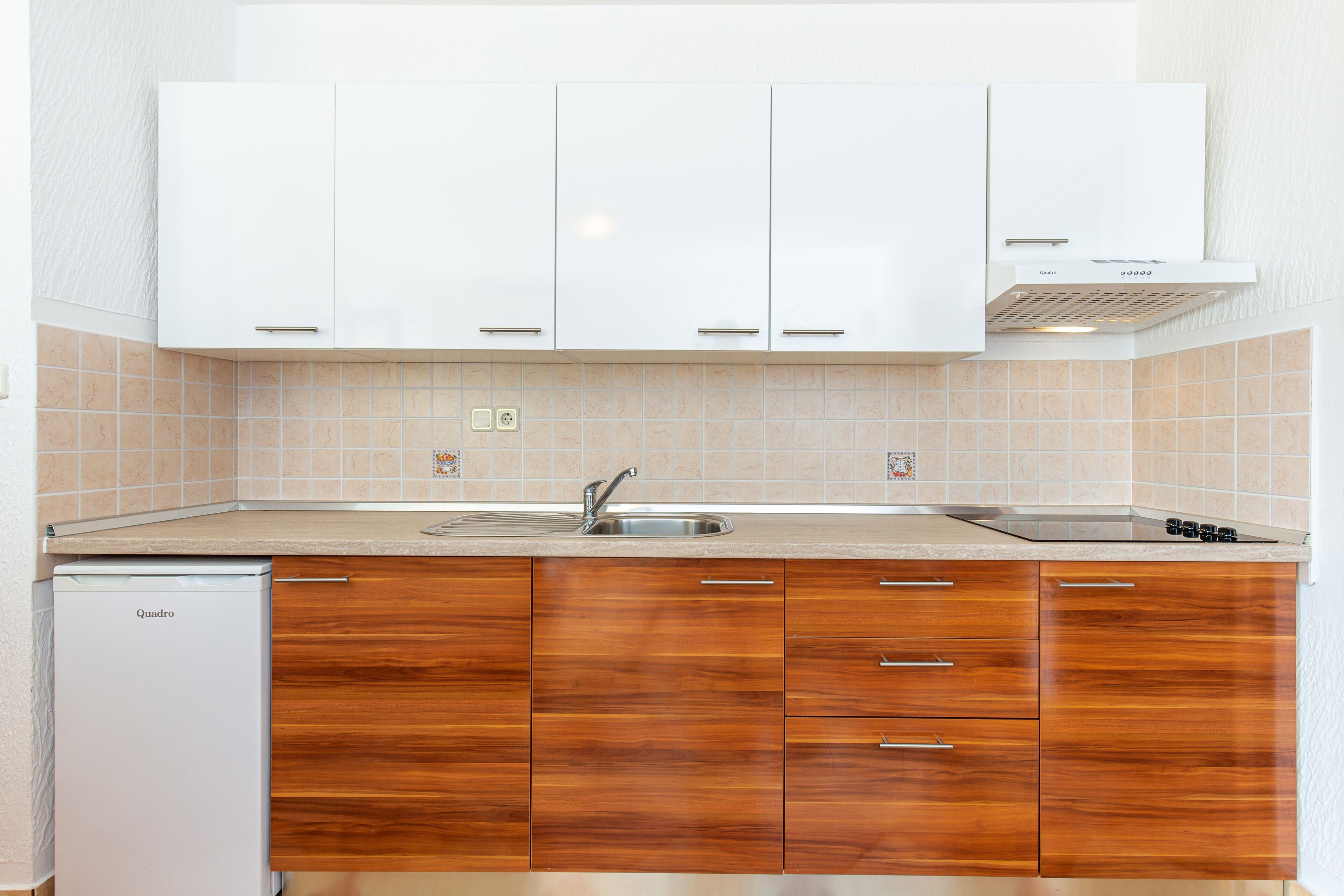 A kitchen with white cabinets, a stainless steel sink, and a dishwasher.