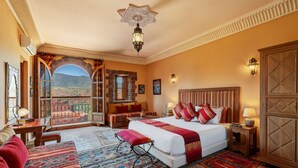Een ruime slaapkamer met een groot bed, een zithoek met uitzicht en een balkon.