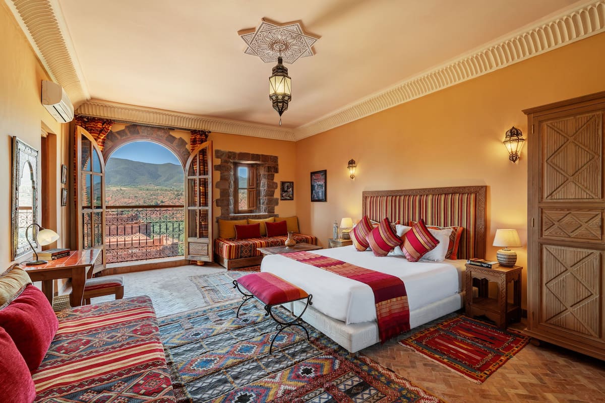 Un dormitorio amplio con una cama grande, una zona de estar con vistas y un balcón.