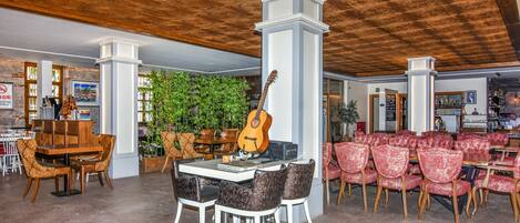 Un hall d’entrée spacieux avec un plafond en bois, une table centrale entourée de chaises, une guitare et une plante verte.