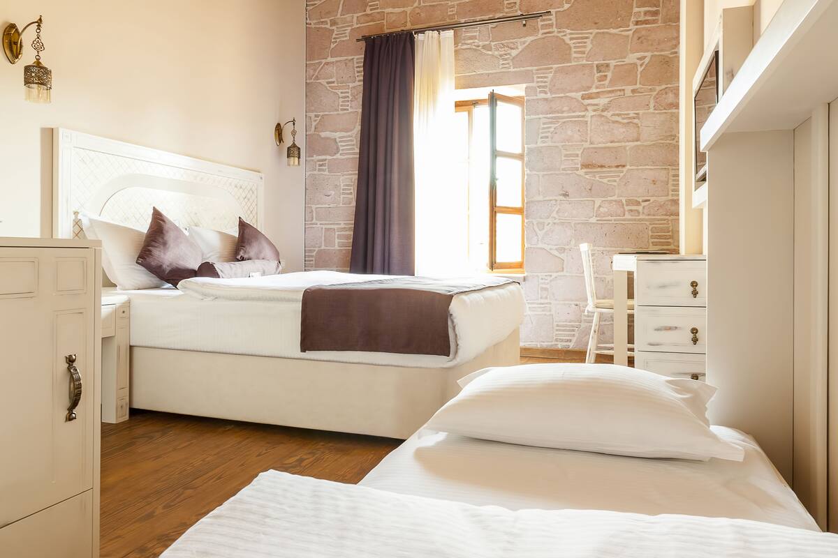 A bedroom with a bed, a desk, and a wardrobe.