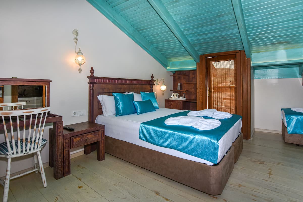 A bedroom with a large bed, a desk, a chair, and a wardrobe.