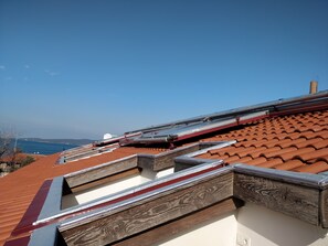 Terraza con tejas de barro y vigas de madera, con vista a una masa de agua.