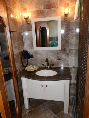 Un baño con lavamanos de mármol, un espejo y apliques de pared.