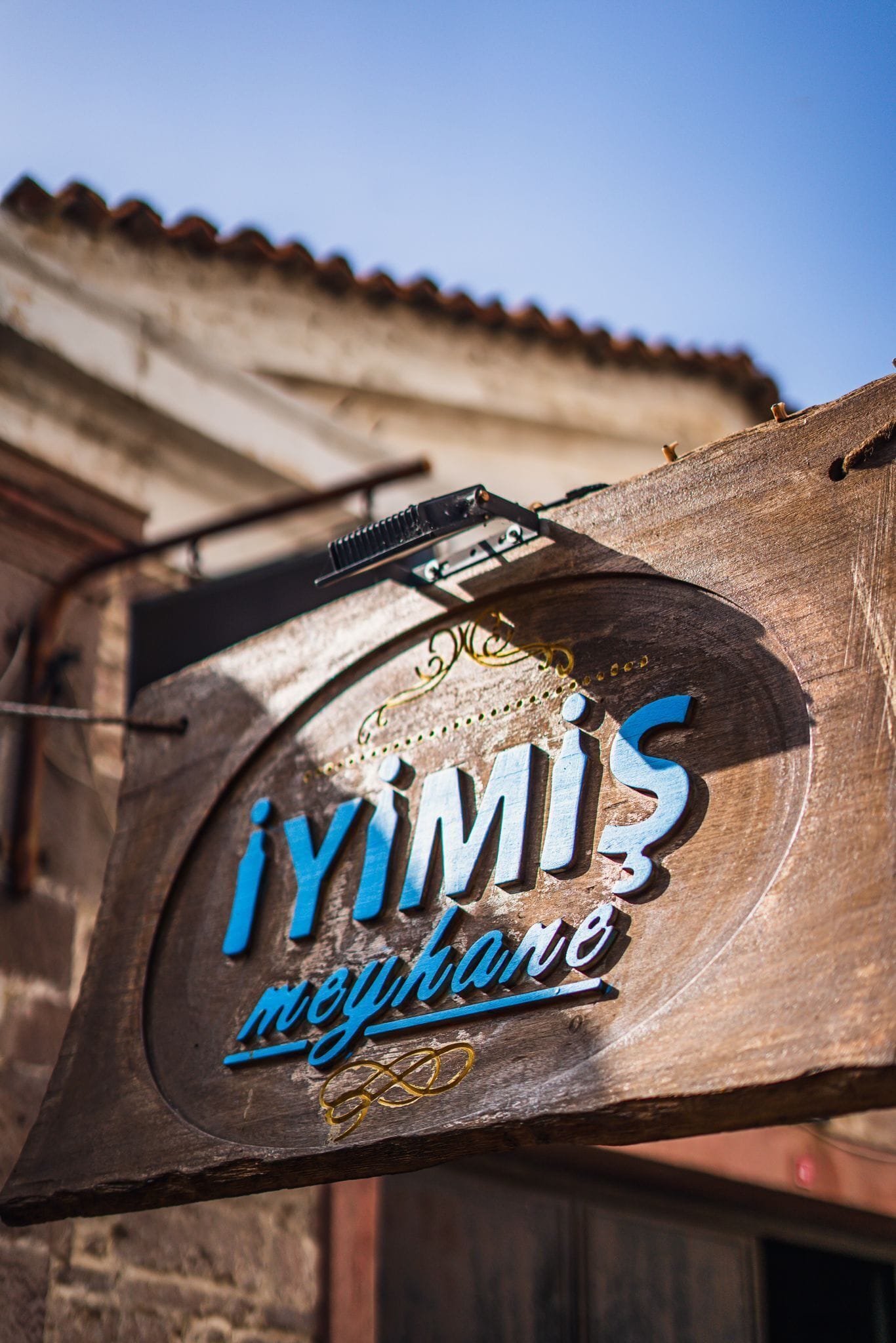 Un letrero de madera con el texto 'İYIMİŞ mahallesi' y 'nephare', indicando un lugar o establecimiento.