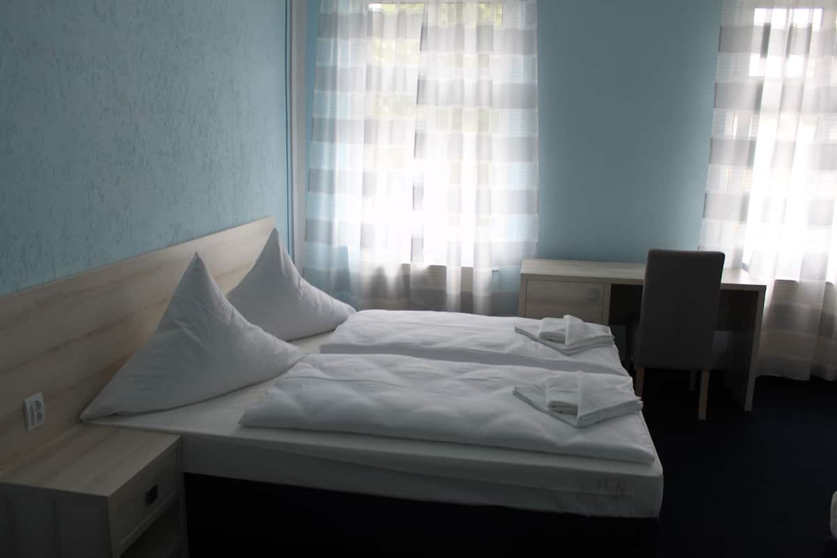 A hotel room with a bed, a desk, and a chair.