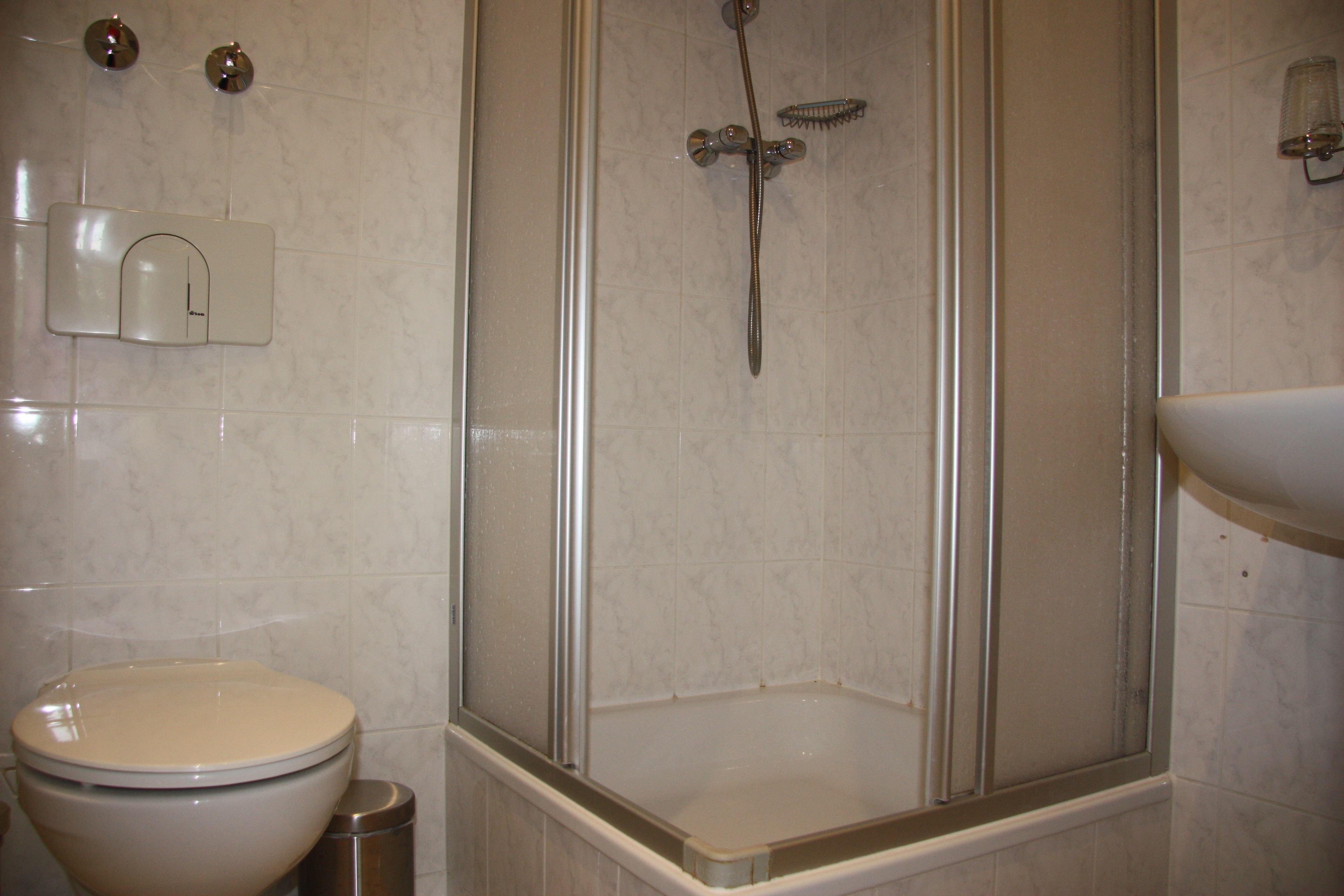Un baño con inodoro, cabina de ducha y lavamanos.