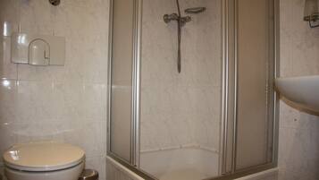 Un baño con inodoro, cabina de ducha y lavamanos.