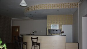 A kitchen with a bar area, wooden chairs, and a patterned wallpaper design. - Hotel am Fluss (Heidesee)