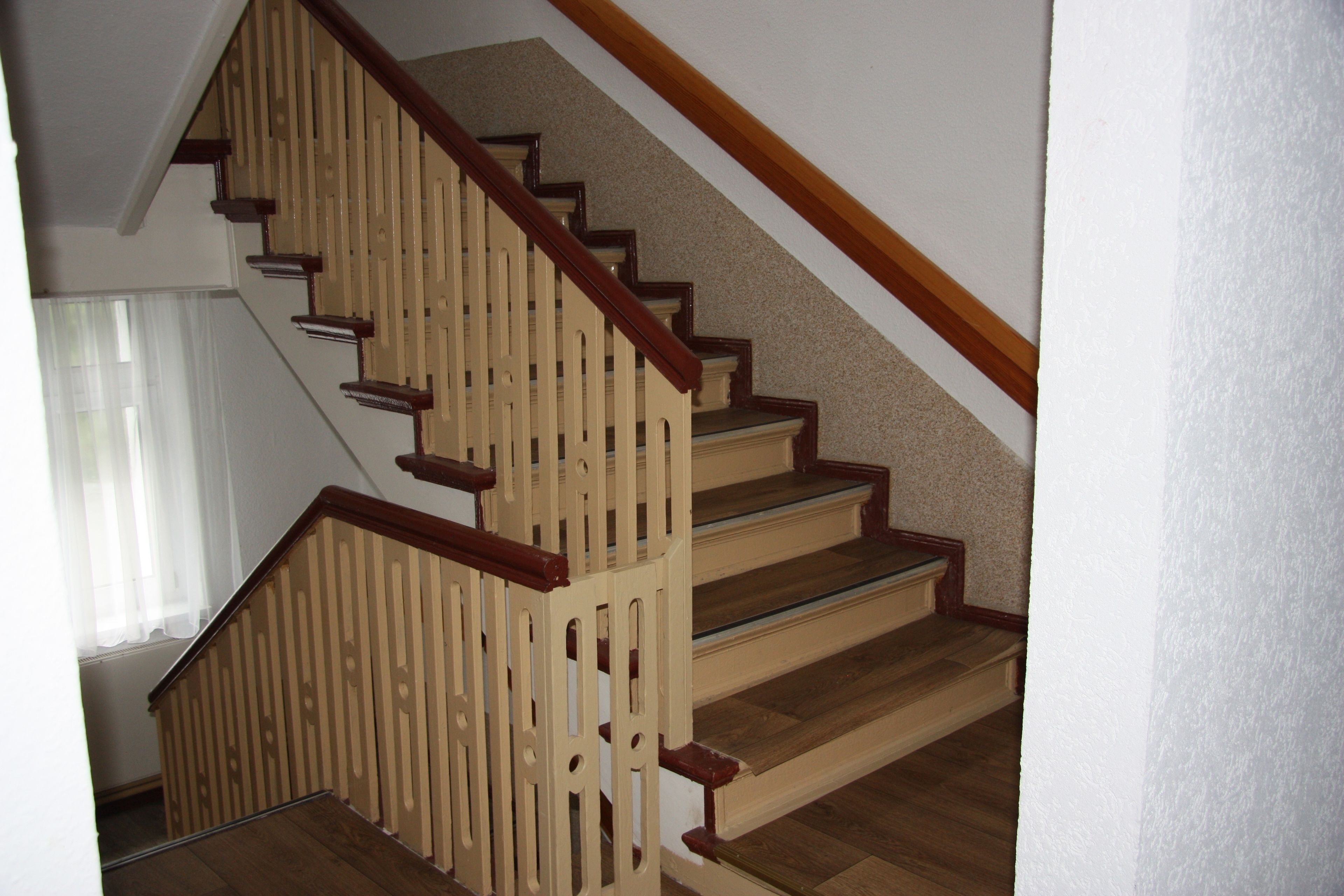 A wooden staircase with a handrail and a landing.