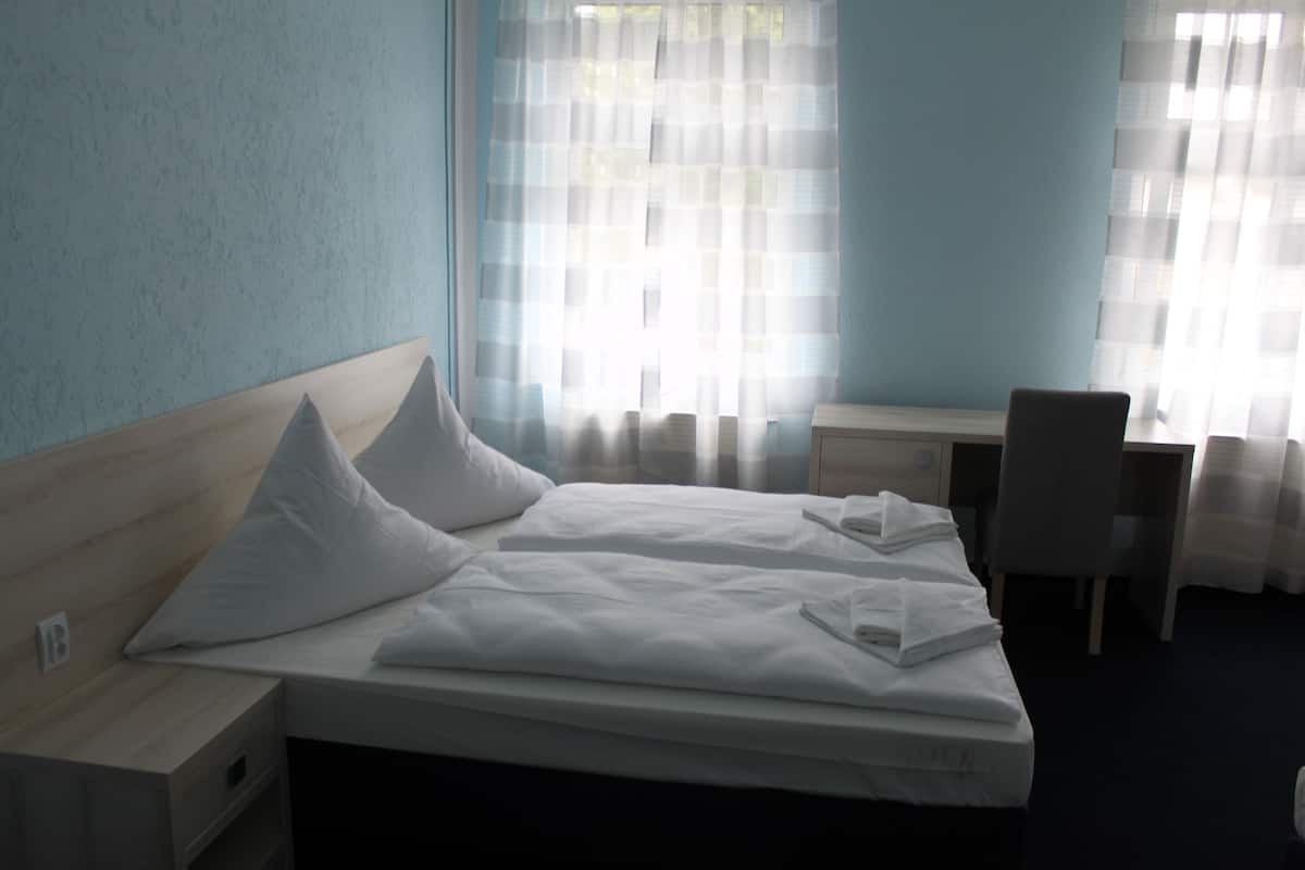 A hotel room with a bed, a desk, and a chair.