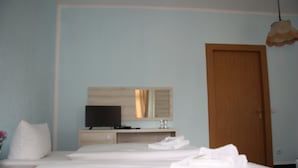 A hotel room with a bed, a television, a wooden door, and a mirror. - Hotel am Fluss (Heidesee)