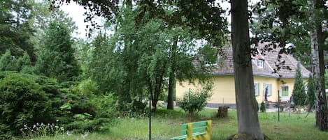 A park with a bench, trees, and a yellow building in the background.