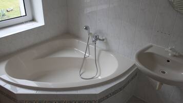 A bathroom with a freestanding bathtub, a sink, and a window.