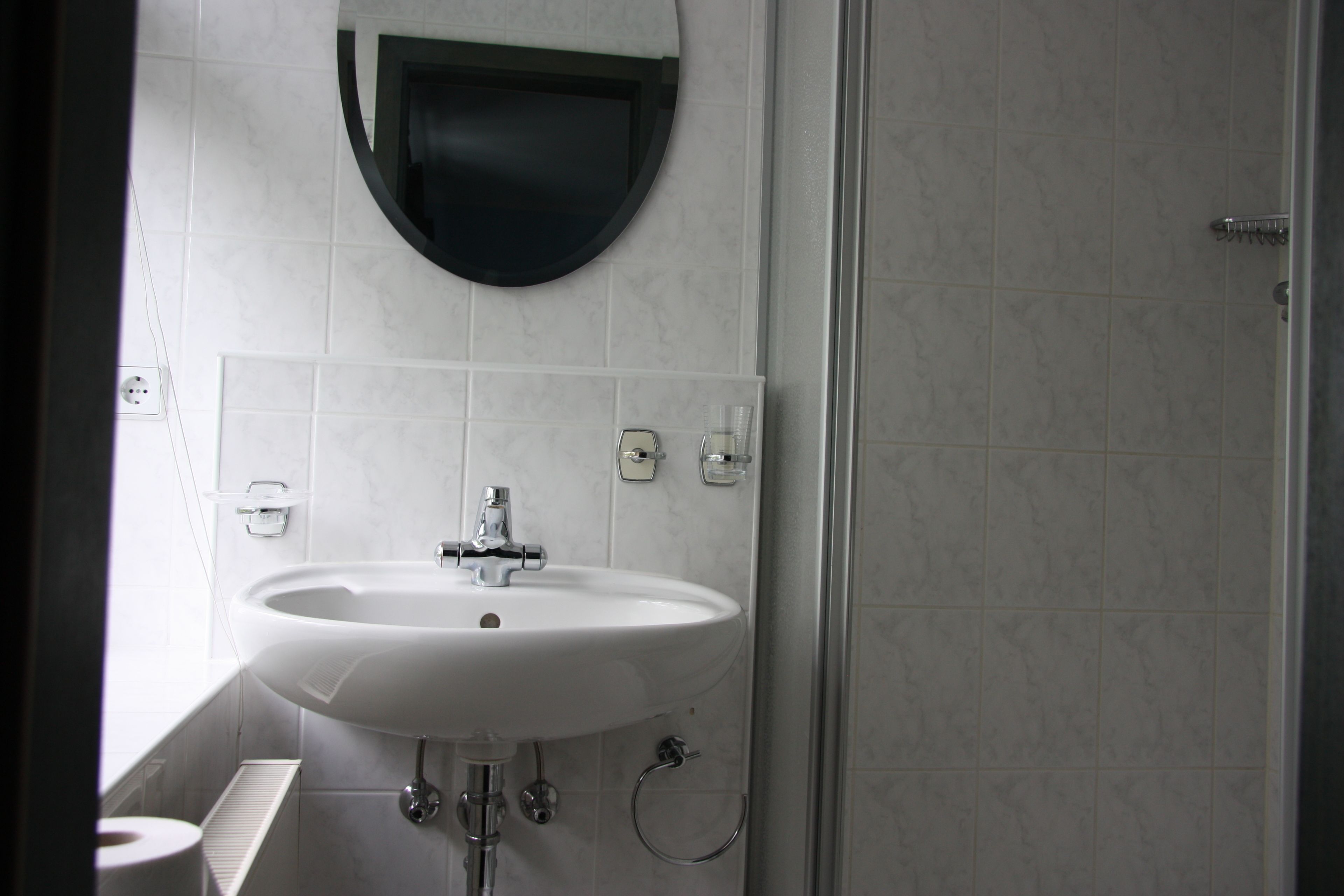 A bathroom with a white sink, a mirror, and a shower area.