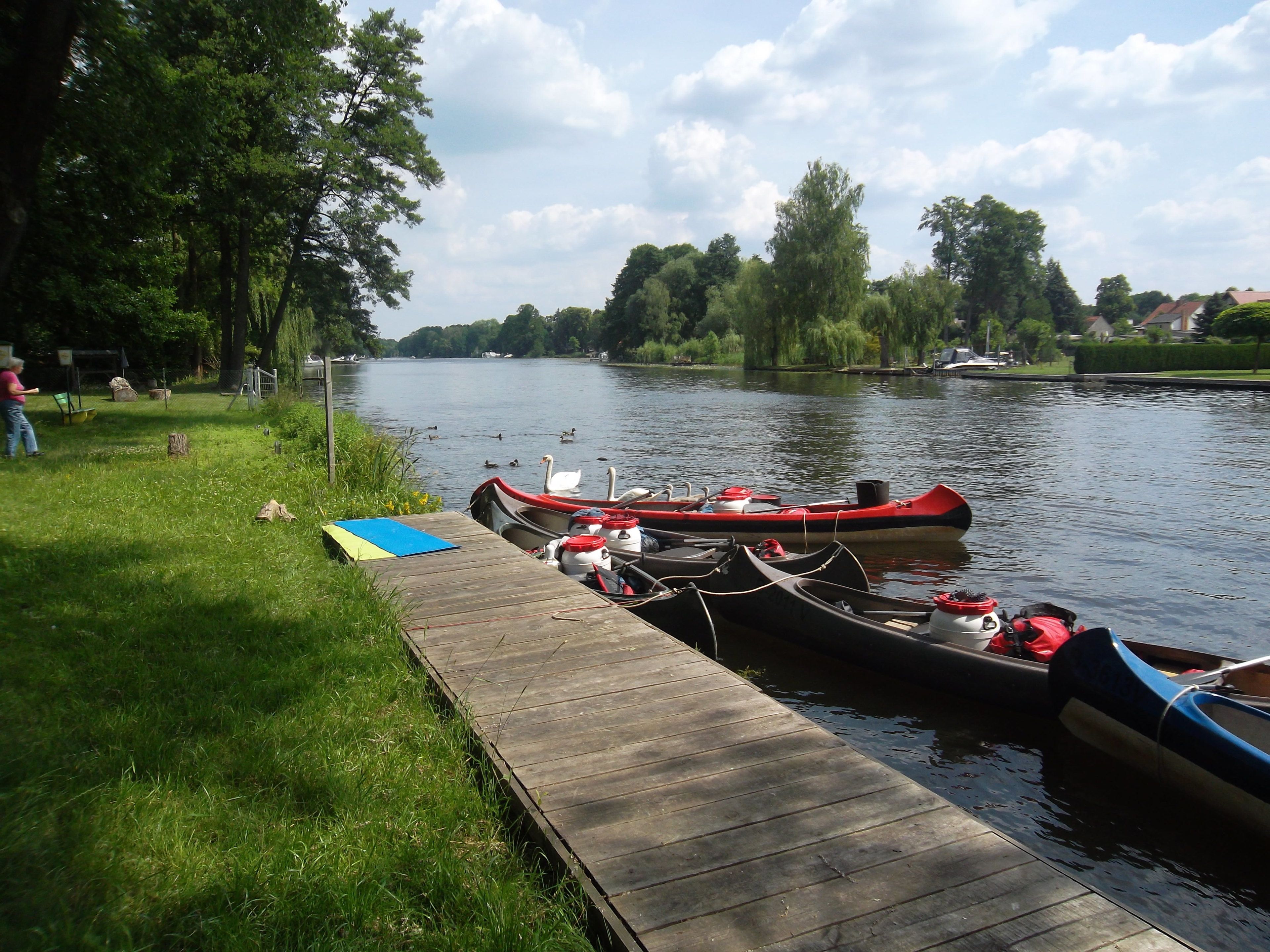 A calm river with boats docked at a wooden pier.