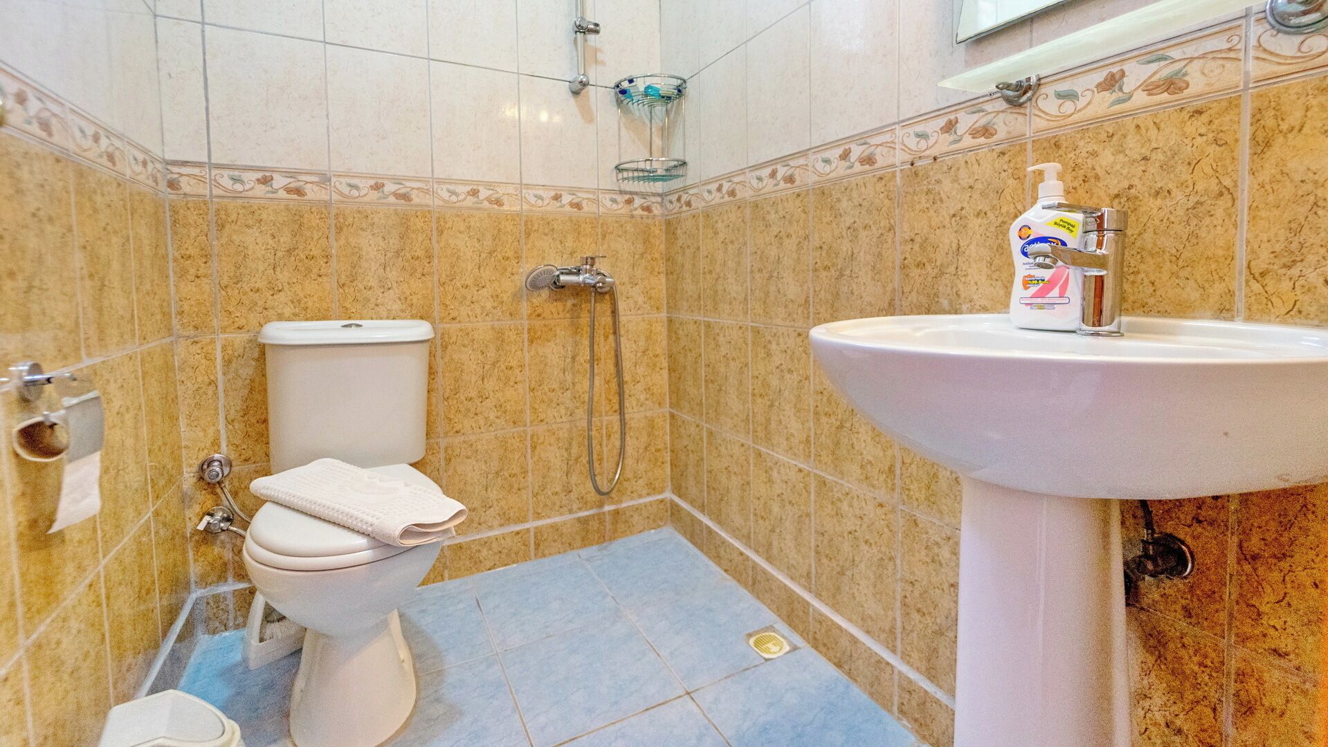 A bathroom with a toilet, shower, and sink.