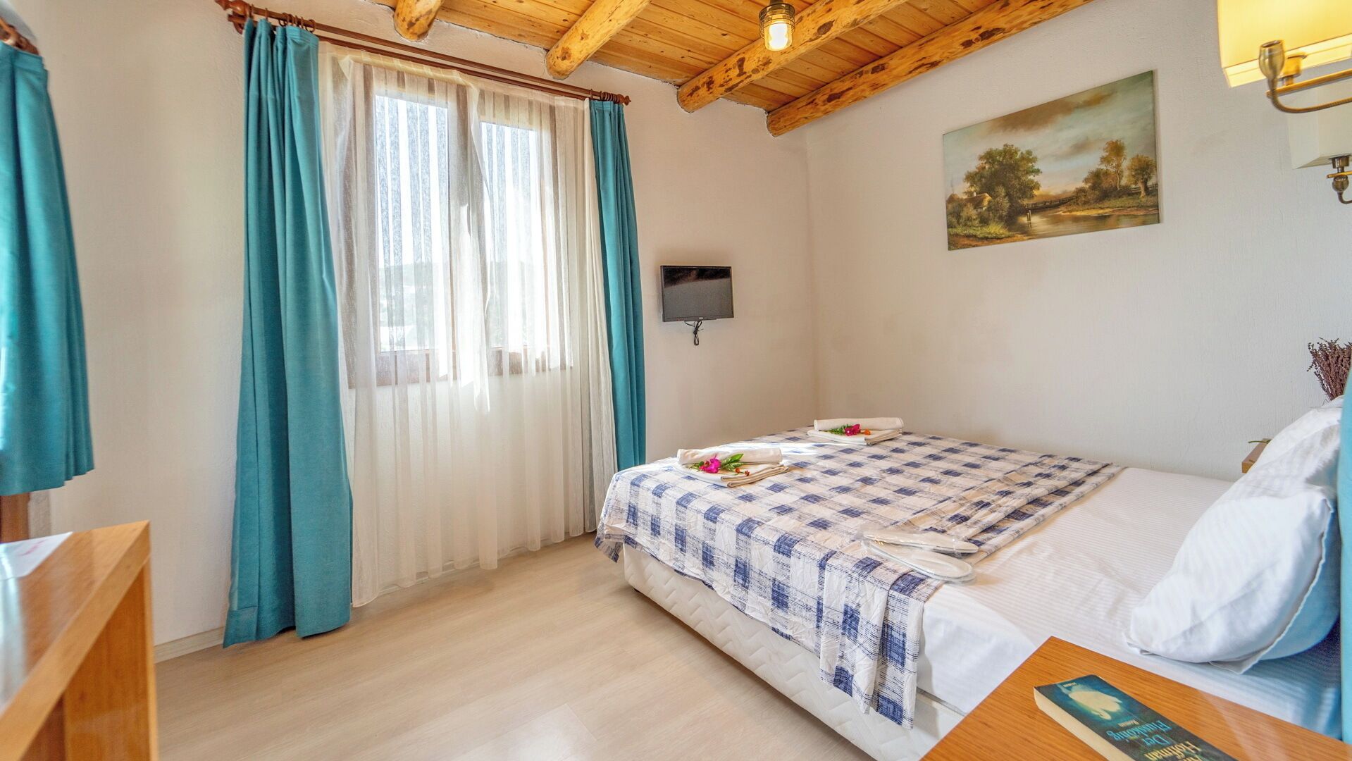 Quarto com cama, televisão, quadro e teto de madeira.