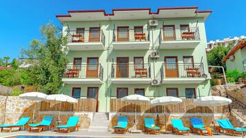 A multi-story hotel with balconies, a swimming pool, and sun loungers.