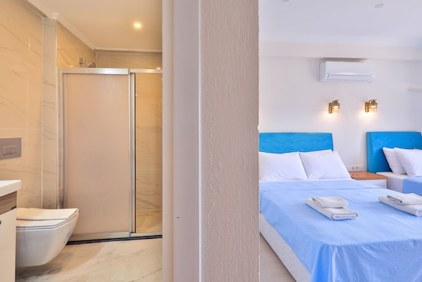 Una habitación de hotel con ducha, una cama con ropa de cama azul y dos mesitas de noche.